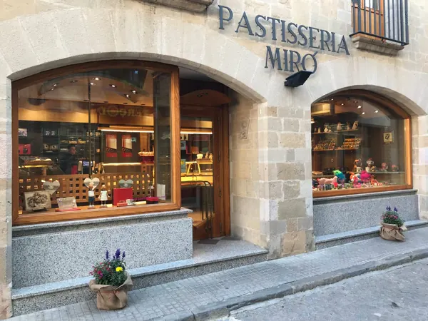 Façana de Pastisseria Miró al carrer Pabordia de Castellterçol: parets de pedra, el rètol amb el nom i dos aparadors en arc