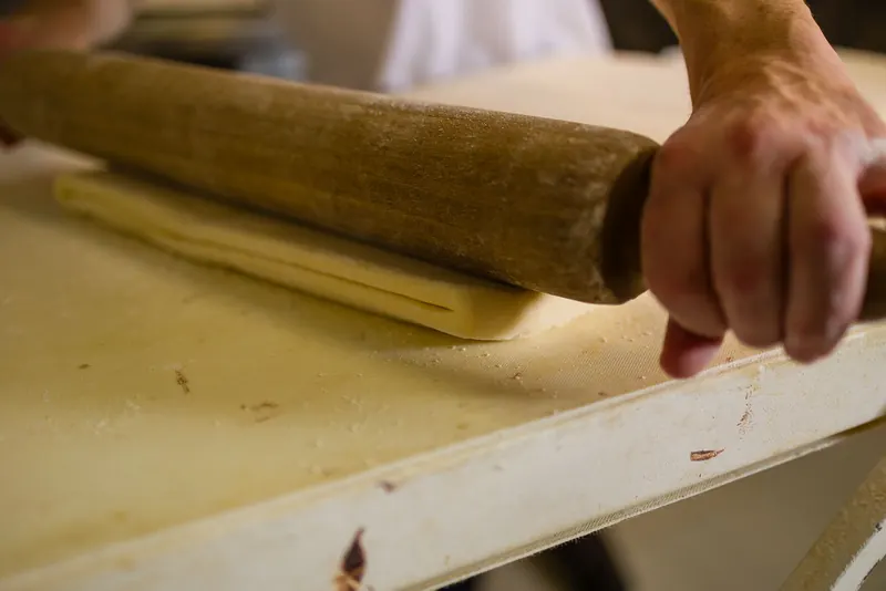 El pastisser estira la massa de full amb el corró