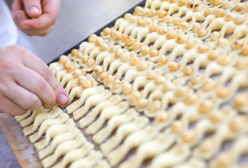 Un pastisser forma pastes amb la màniga, una a una, sobre la safata